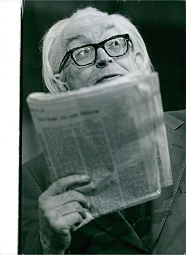 Гроздобер фотографија на Мајкл Мекинтош стапало што држи весник и гледа во нешто.